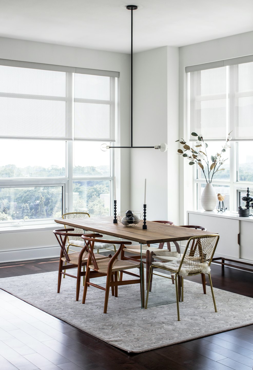 Dining room with light wooden table and mixed chairs.